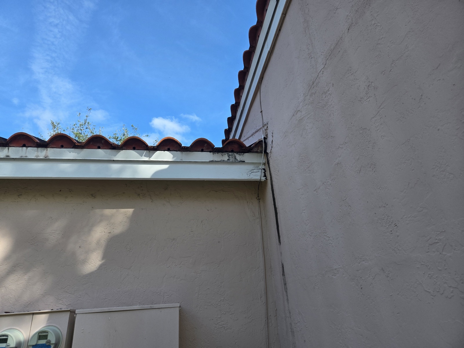 Rotted and stained fascia board under a tile roof edge on a Miami home